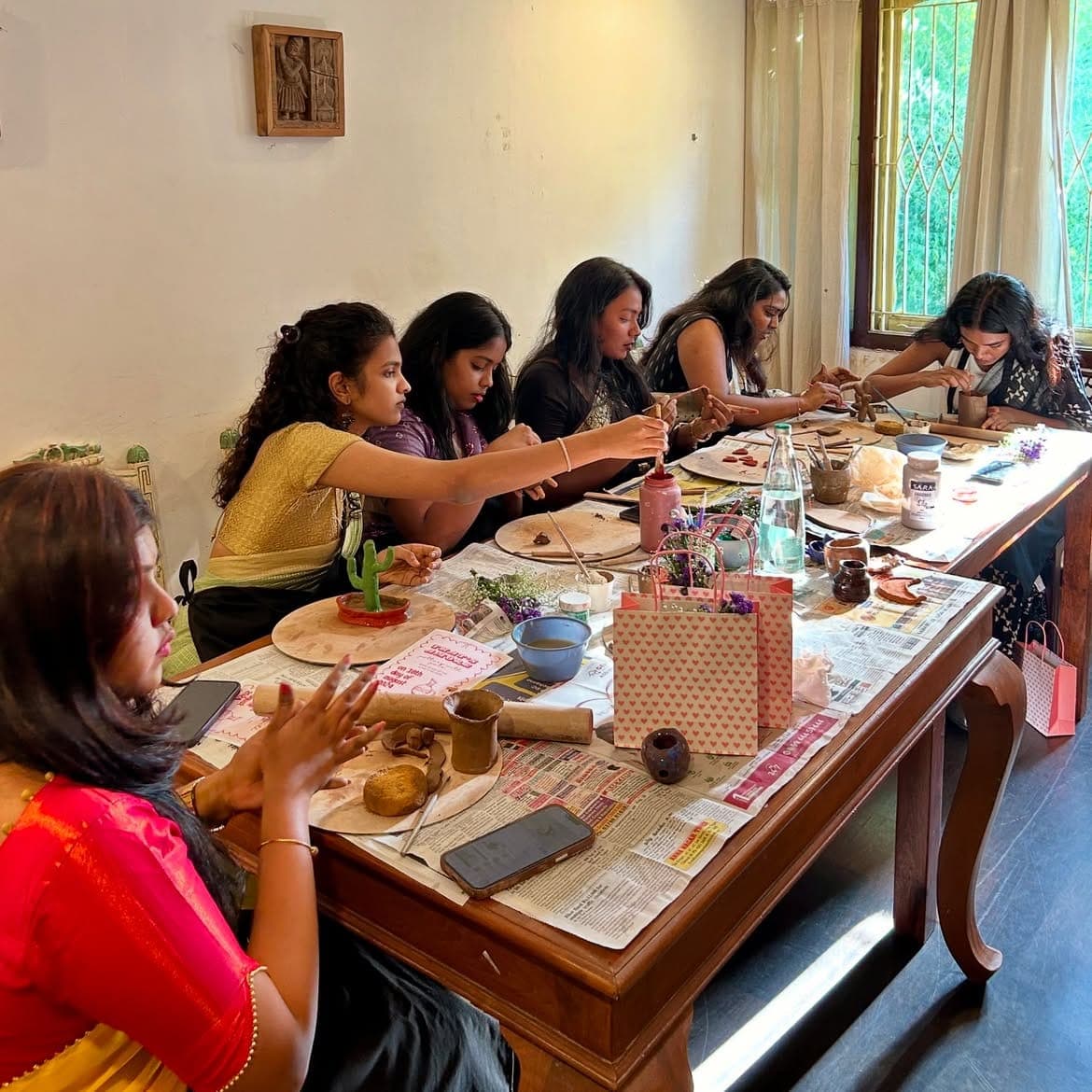 A group working with clay around the studio's long wooden table